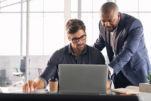 Two men examining a laptop screen together